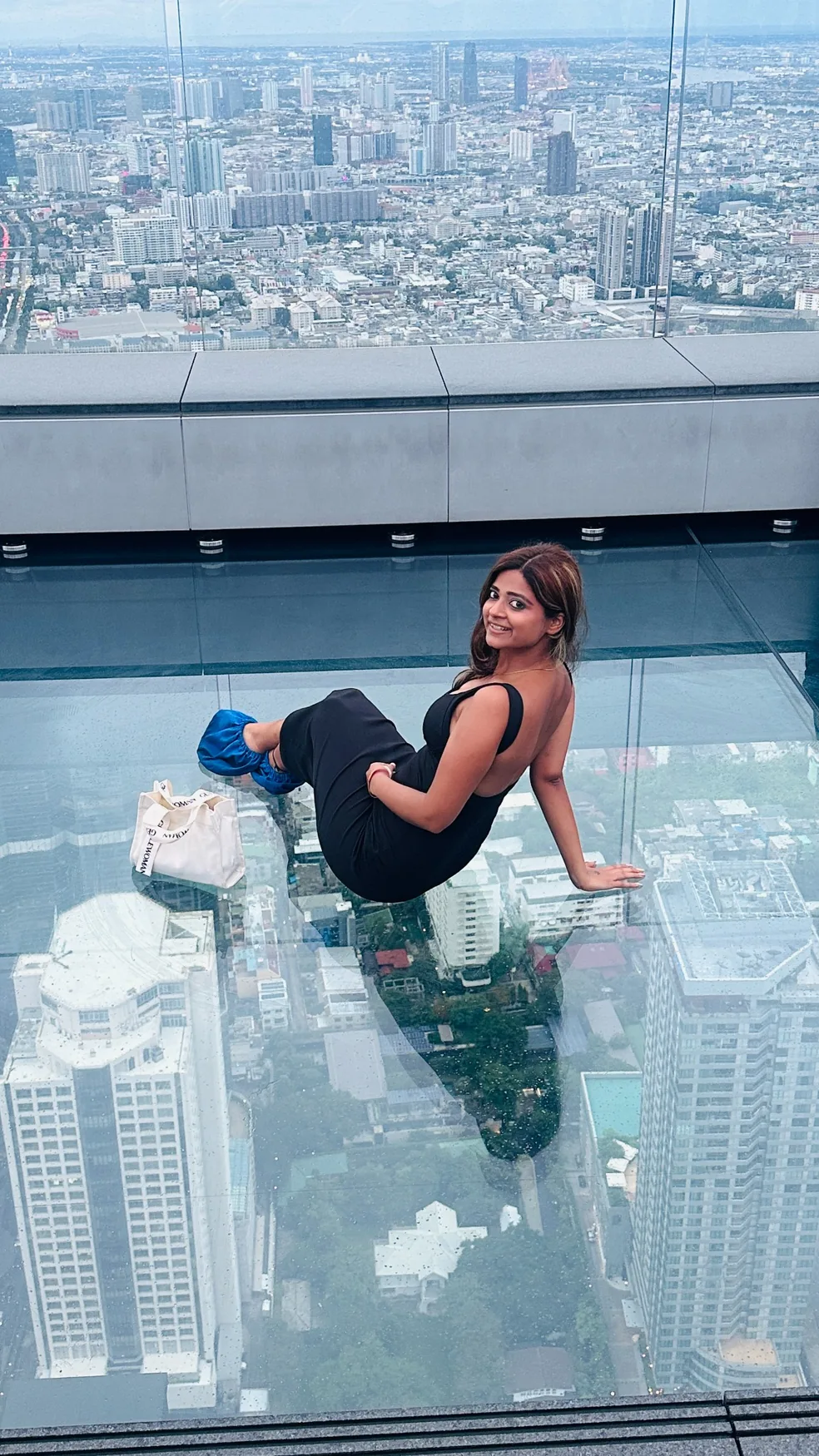 Lavanya on a high-rise glass observation deck with a view of the city